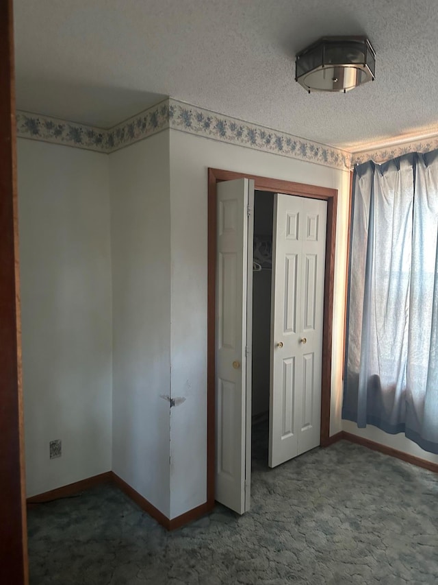 unfurnished bedroom featuring a textured ceiling, carpet, and a closet