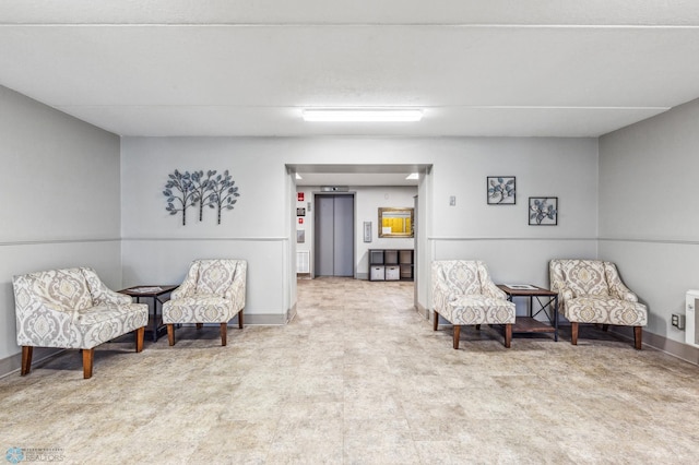 living area featuring elevator and baseboards