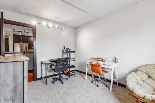 carpeted office space featuring a textured ceiling and baseboards