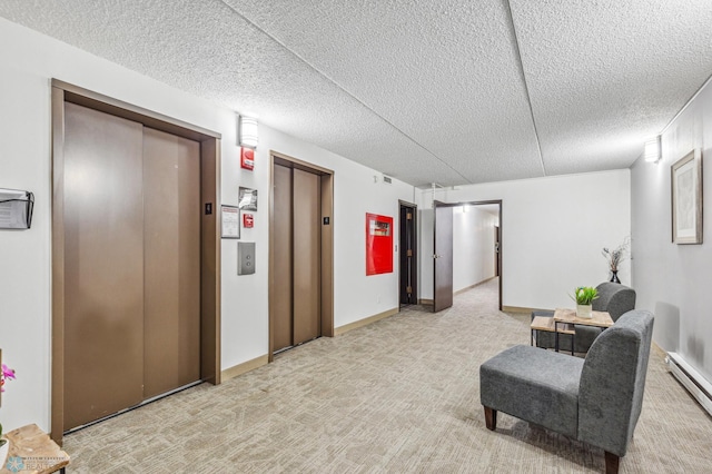 sitting room featuring elevator, a baseboard heating unit, and light colored carpet