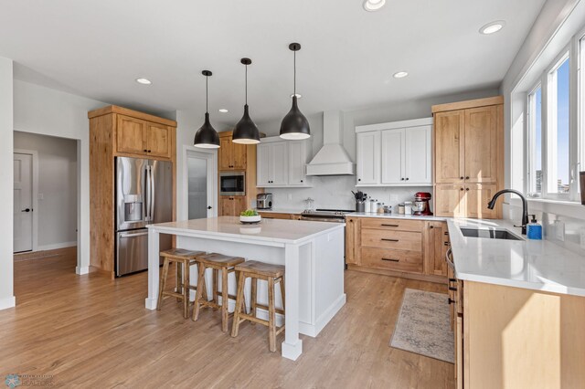 kitchen with a center island, appliances with stainless steel finishes, a wealth of natural light, and premium range hood