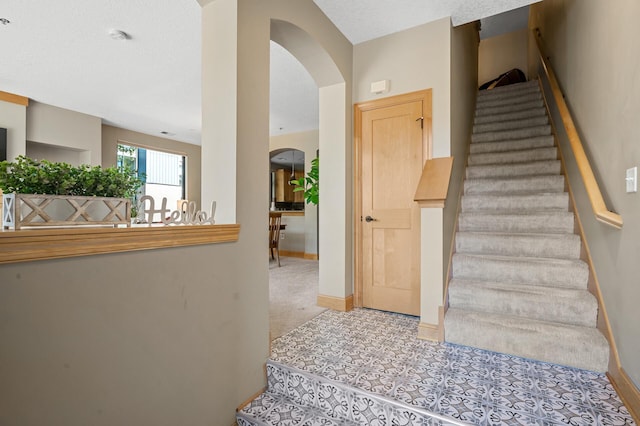 staircase featuring carpet flooring and a textured ceiling