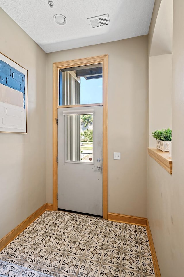 doorway to outside featuring a textured ceiling and tile patterned floors