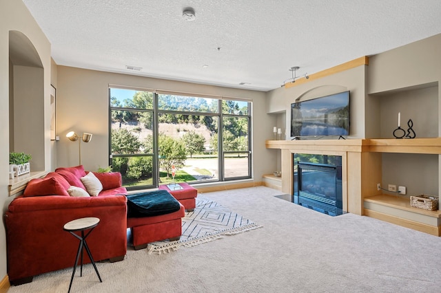 living room with a textured ceiling, carpet flooring, and a high end fireplace