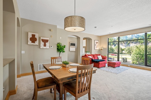 dining space featuring a textured ceiling and light colored carpet