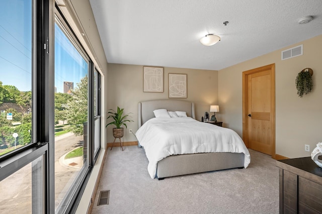 bedroom with light colored carpet and a textured ceiling