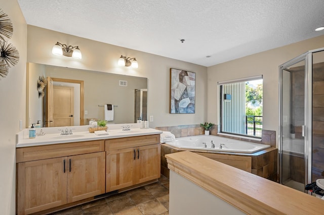 bathroom with a textured ceiling, vanity, and plus walk in shower