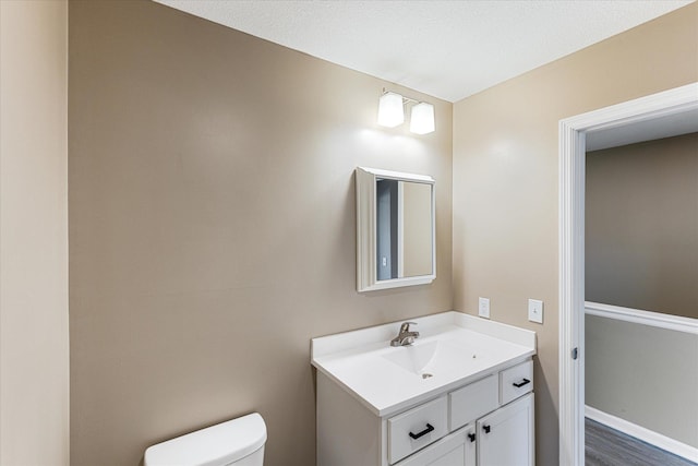 bathroom with hardwood / wood-style floors, toilet, and vanity