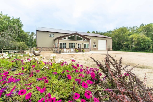 view of front of house featuring stone siding, driveway, a garage, and fence