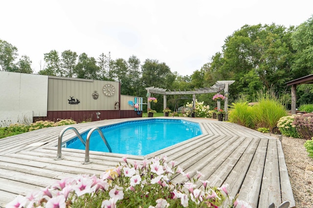 pool with a pergola, a deck, and fence