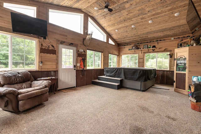 carpeted living area featuring high vaulted ceiling, wood walls, wood ceiling, and ceiling fan