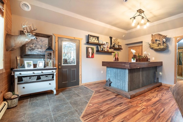 interior space featuring a baseboard heating unit, a dry bar, wood finished floors, and visible vents