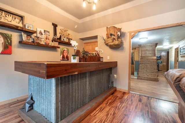 bar with baseboards, a dry bar, stairs, wood finished floors, and stainless steel appliances