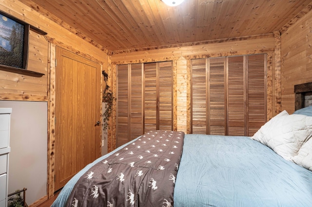 bedroom featuring two closets, wood ceiling, and wood walls