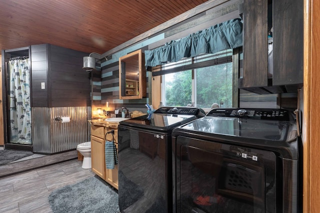 clothes washing area featuring light wood finished floors, wood ceiling, laundry area, independent washer and dryer, and a sink