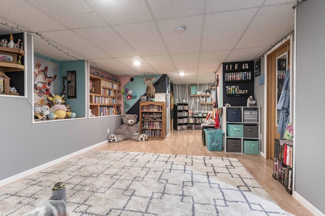 finished basement featuring a paneled ceiling, baseboards, and wood finished floors