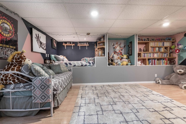 interior space featuring a paneled ceiling, baseboards, and wood finished floors