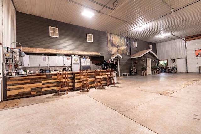 interior space featuring concrete floors, a dry bar, and metal wall