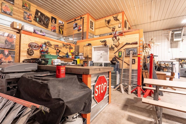 miscellaneous room featuring a workshop area, concrete flooring, and wooden walls