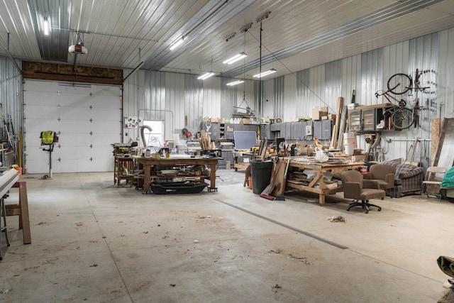 garage featuring metal wall, a workshop area, and a garage door opener