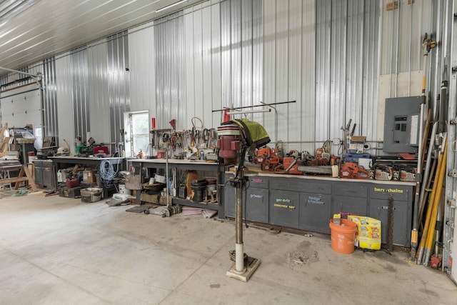 garage with electric panel, a workshop area, and metal wall