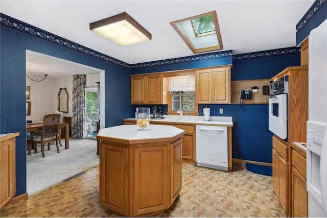 kitchen featuring white appliances, a skylight, and a kitchen island