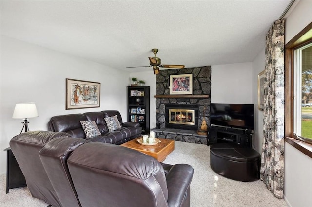 living room featuring a textured ceiling, a stone fireplace, and ceiling fan