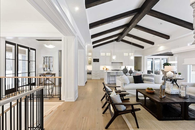 living room featuring lofted ceiling with beams, a notable chandelier, and light wood-type flooring