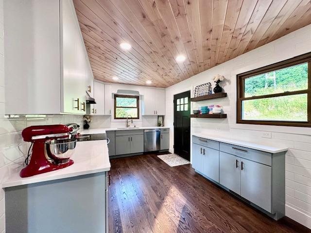 kitchen featuring stainless steel appliances, a sink, light countertops, gray cabinets, and open shelves