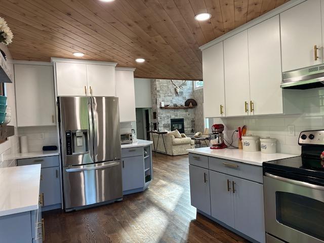 kitchen with stainless steel appliances, light countertops, open floor plan, white cabinets, and under cabinet range hood