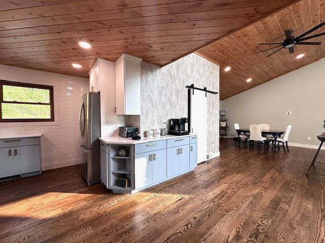 kitchen featuring light countertops, a barn door, freestanding refrigerator, white cabinetry, and wooden ceiling