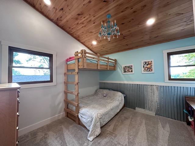 bedroom featuring lofted ceiling, a chandelier, carpet flooring, wood ceiling, and wainscoting