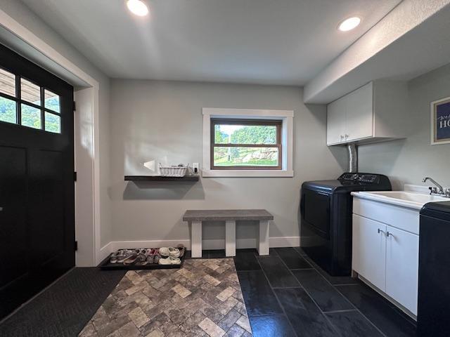 clothes washing area featuring washer and clothes dryer, a sink, cabinet space, and a healthy amount of sunlight