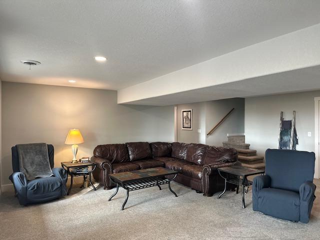 living area with visible vents, light colored carpet, stairs, a textured ceiling, and recessed lighting