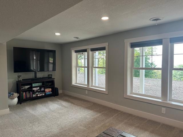 living room with carpet floors, a healthy amount of sunlight, a textured ceiling, and baseboards