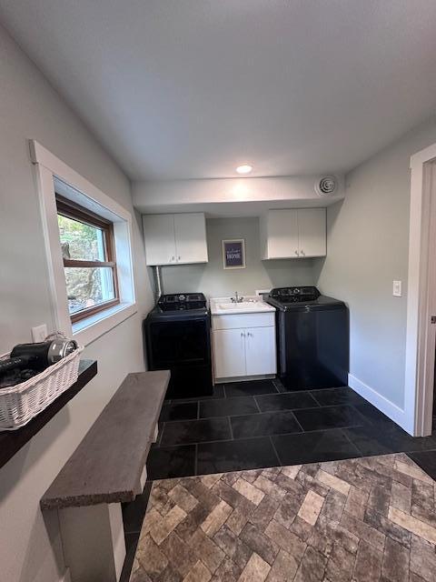 kitchen featuring baseboards, white cabinetry, a sink, and independent washer and dryer