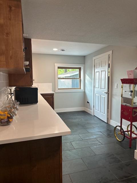 kitchen featuring light countertops, backsplash, and baseboards