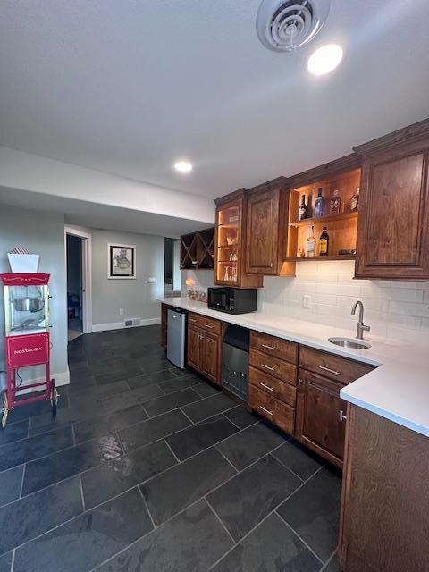 kitchen with dishwasher, light countertops, black microwave, open shelves, and a sink