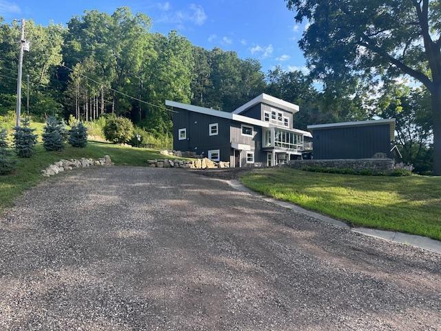 view of front of house featuring gravel driveway and a front lawn