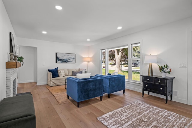 living room with a brick fireplace and light hardwood / wood-style flooring