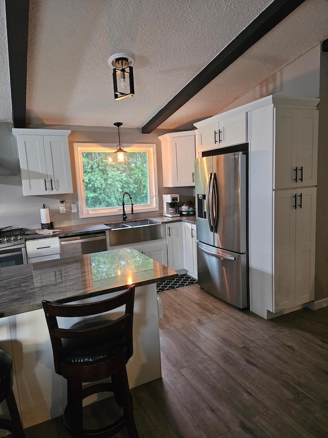 kitchen with stainless steel appliances, dark wood-type flooring, a sink, white cabinetry, and beamed ceiling