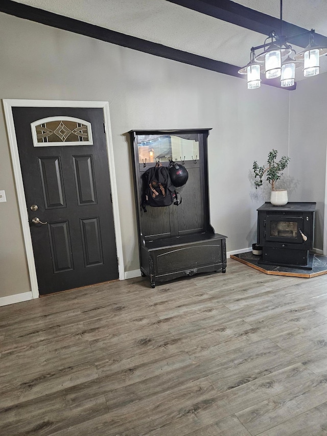 entrance foyer featuring a wood stove, baseboards, and wood finished floors