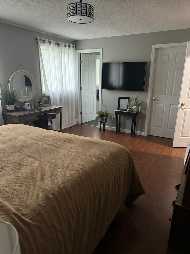 bedroom featuring dark wood finished floors, a textured ceiling, and baseboards