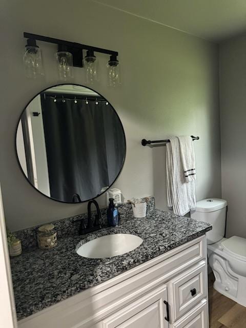 bathroom featuring toilet, wood finished floors, and vanity