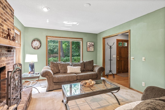 living room with light wood-type flooring, a textured ceiling, a brick fireplace, and brick wall