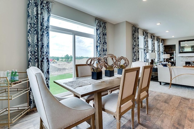 dining room featuring a stone fireplace and light hardwood / wood-style flooring