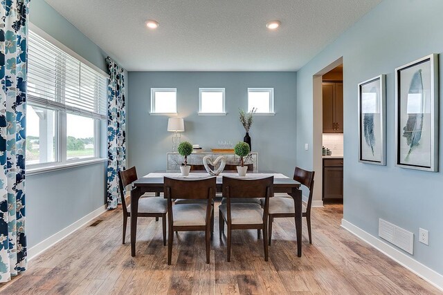 dining area featuring light hardwood / wood-style floors and a textured ceiling