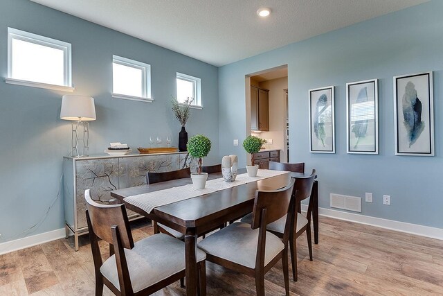 dining space with light hardwood / wood-style flooring and a textured ceiling