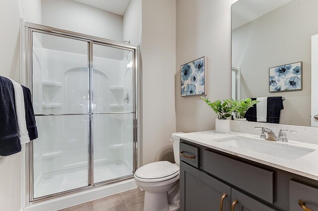 bathroom featuring vanity, a shower with shower door, toilet, and tile patterned floors