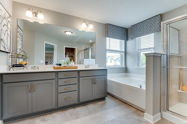 bathroom with vanity, independent shower and bath, a textured ceiling, and tile patterned flooring